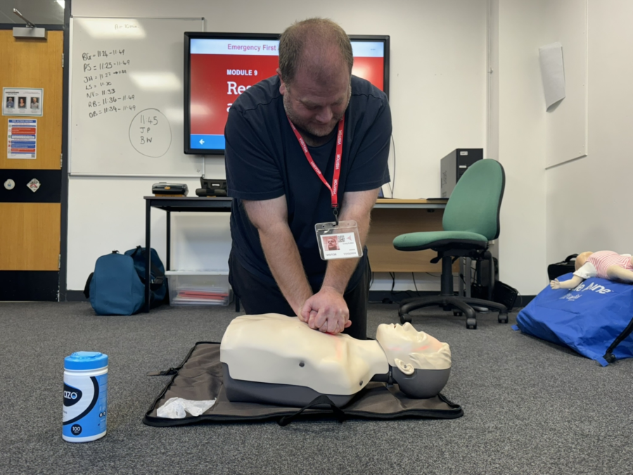 A person giving CPR on a practice dummy during first aid training.