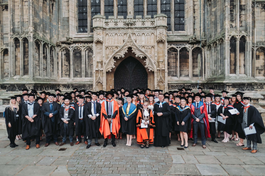 A large group of graduates celebrate their Graduation in front of the Stump in Boston.